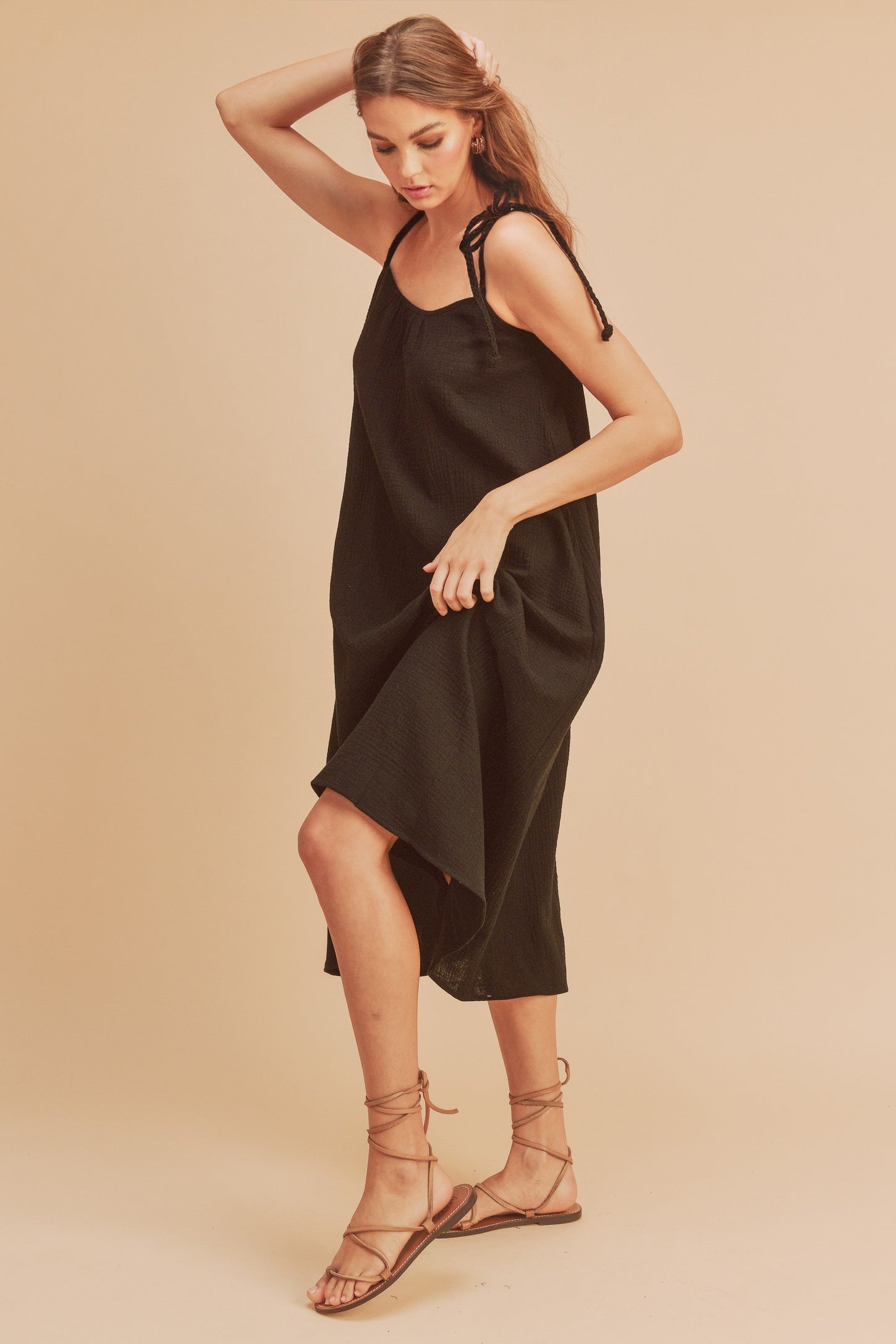 woman wearing a black sleeveless dress with adjustable straps and a flowy silhouette
