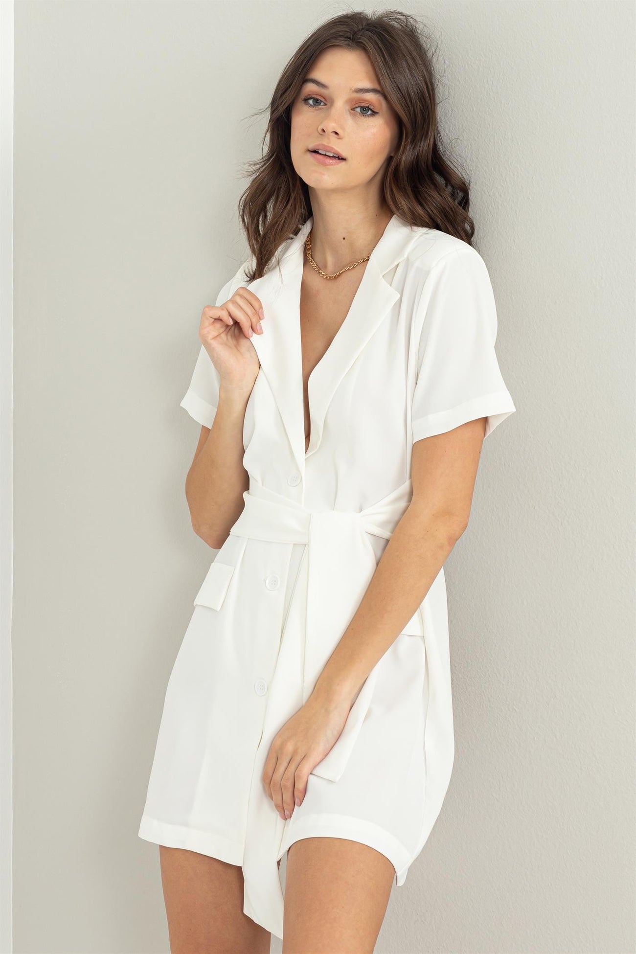 woman wearing a white short-sleeve belted shirt dress with a V-neck and pockets