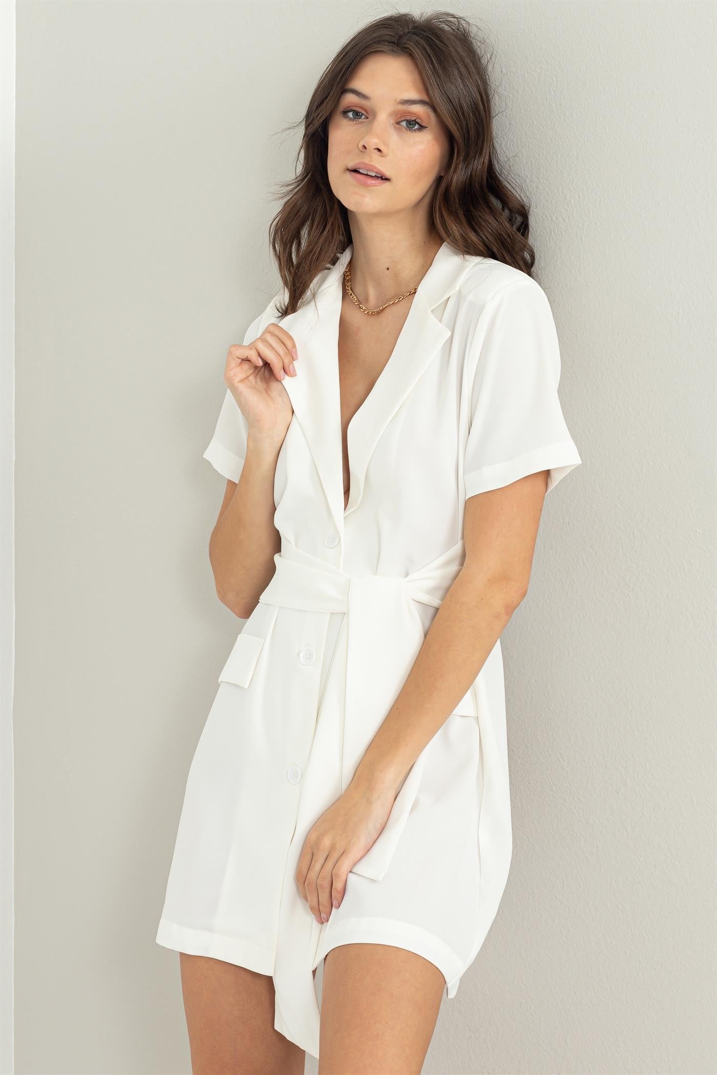woman wearing a white short-sleeve belted shirt dress with a V-neck and pockets