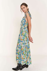 woman wearing a blue floral maxi dress with ruffle straps and a tiered skirt, styled with black ankle boots