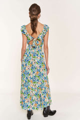 woman wearing a colorful floral maxi dress with ruffle sleeves and an open back, paired with black ankle boots