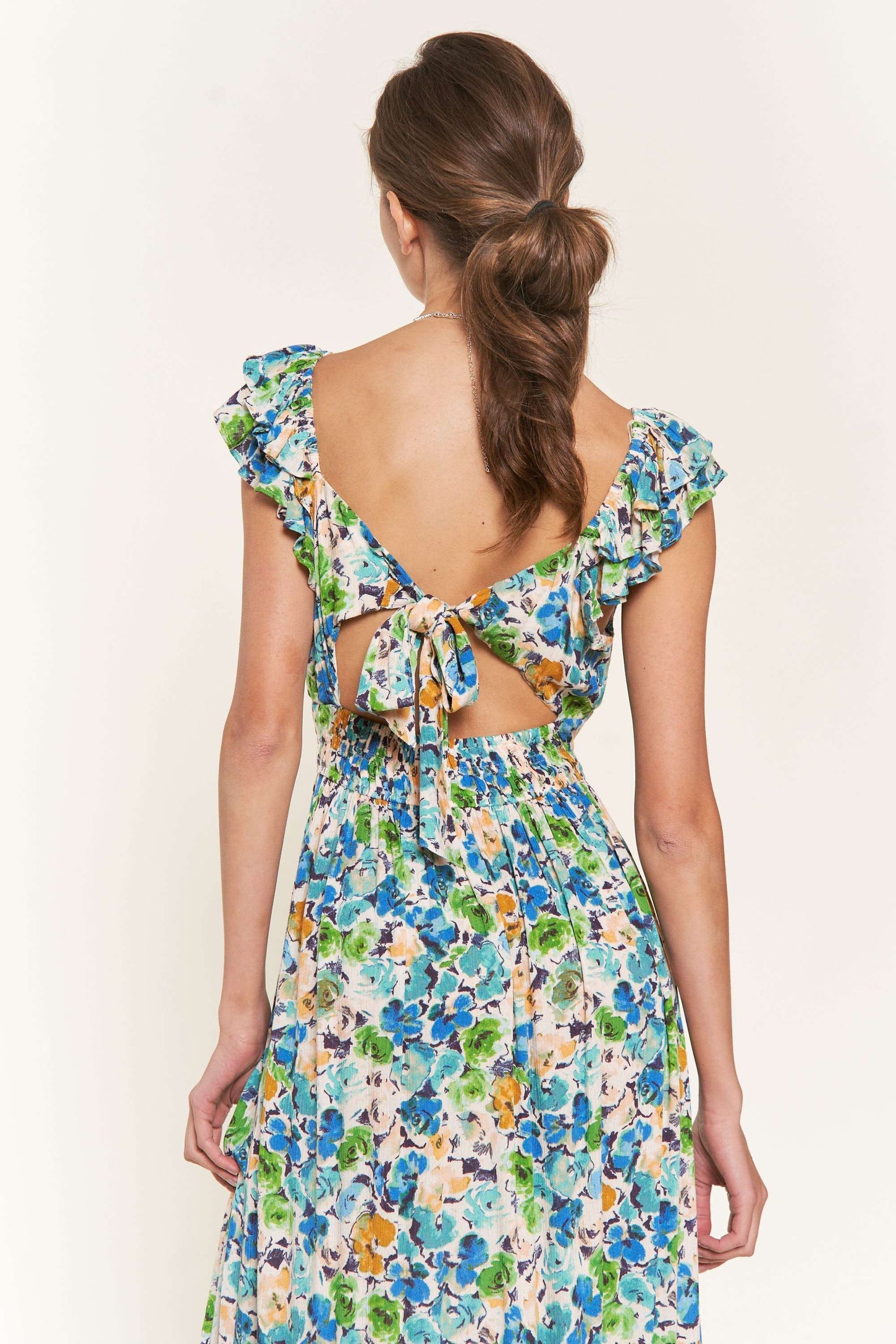 woman wearing a floral backless maxi dress with ruffle sleeves and a tied back detail