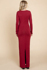 woman wearing a burgundy long sleeve form-fitting maxi dress with a back slit