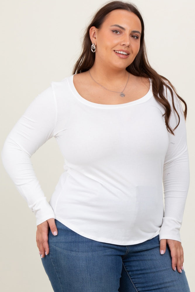 woman wearing a white long sleeve top paired with blue jeans, smiling and posing against a neutral background