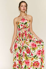 woman wearing a floral maxi dress with a halter neck and cut-out details in shades of pink and green