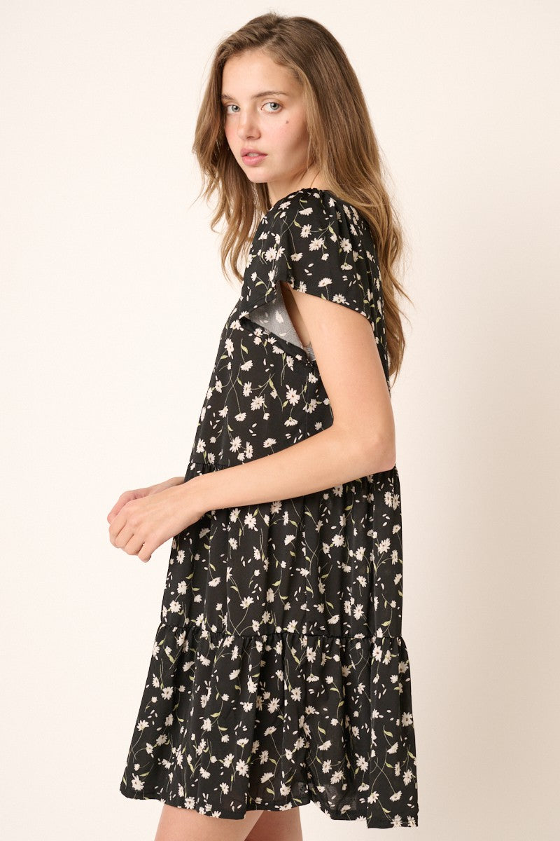 woman wearing a black floral short sleeve dress with a tiered skirt