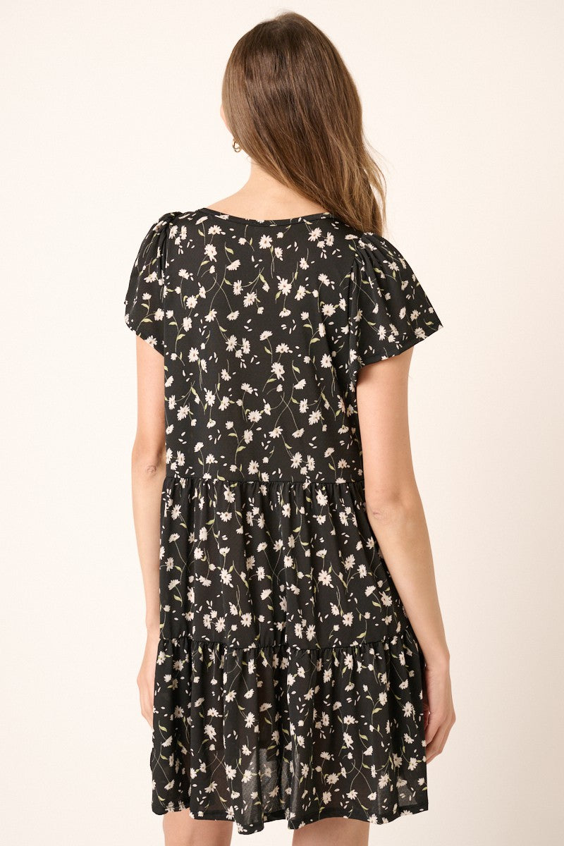 woman wearing a black floral print short sleeve dress with a tiered skirt