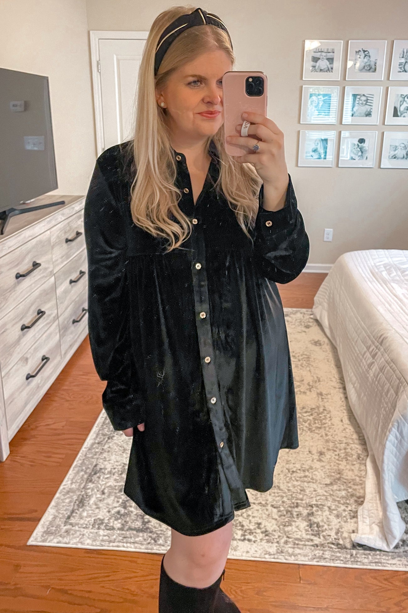 woman wearing a black velvet long sleeve button-up dress, posing with a headband and holding a phone