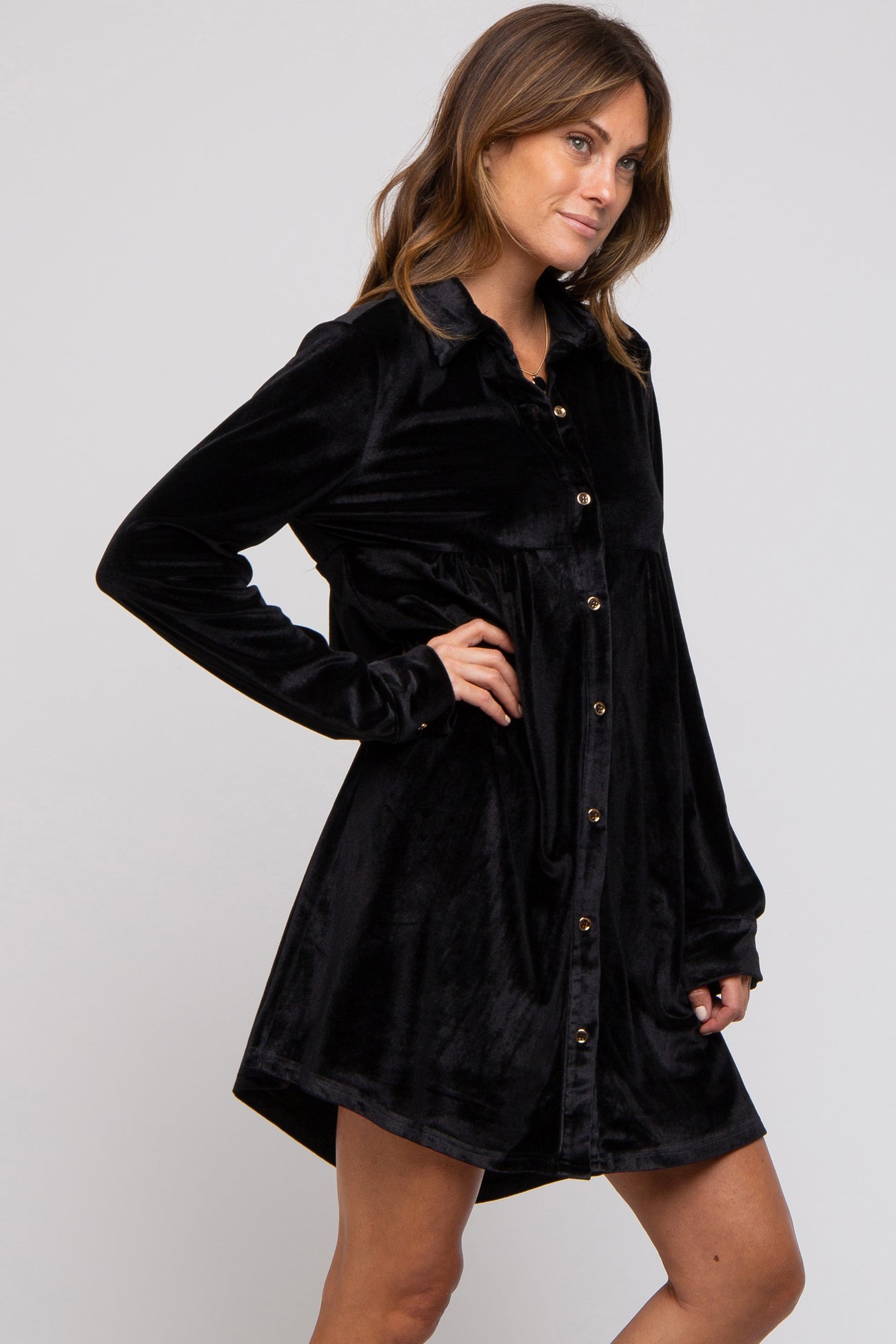 woman wearing a black velvet long sleeve button-up dress with a relaxed fit and a rounded hem
