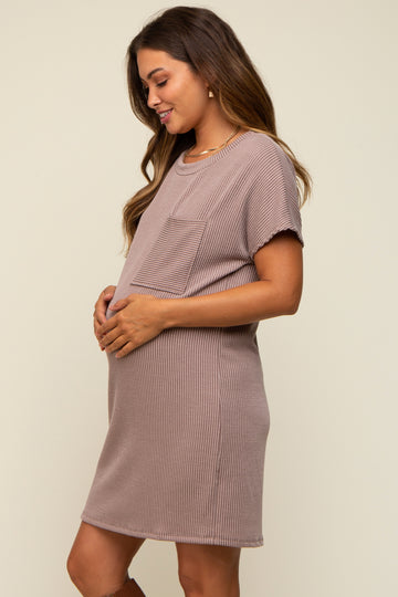 woman wearing a taupe ribbed maternity dress with a pocket, gently cradling her baby bump