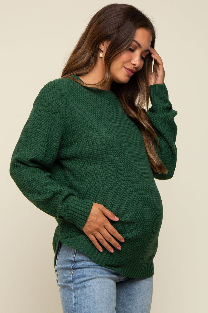 woman wearing a green maternity sweater and holding her baby bump