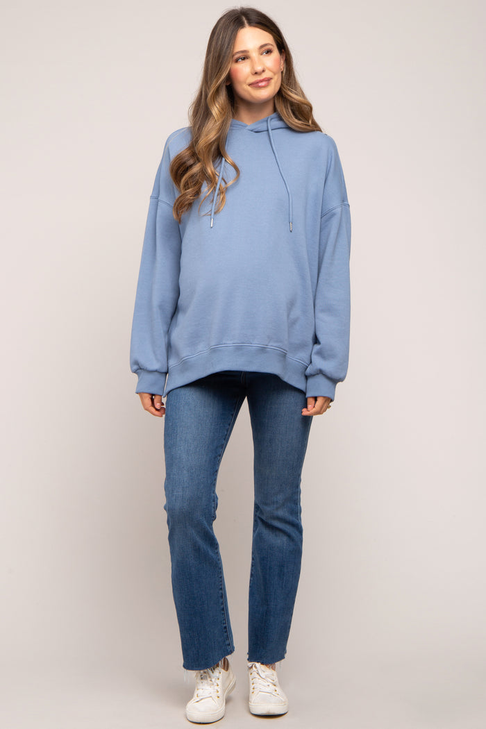 woman wearing a light blue oversized hoodie and skinny jeans, showing her baby bump