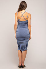 woman wearing a blue ruched maternity midi dress with crisscross back details