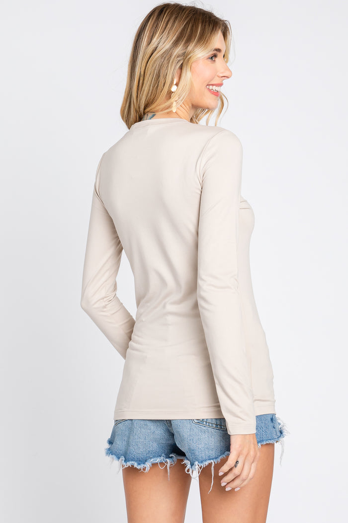 woman wearing a beige long sleeve top with a scoop neckline and back view, paired with denim shorts