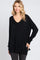woman wearing a black oversized v-neck sweater with long sleeves and side slits, smiling at the camera