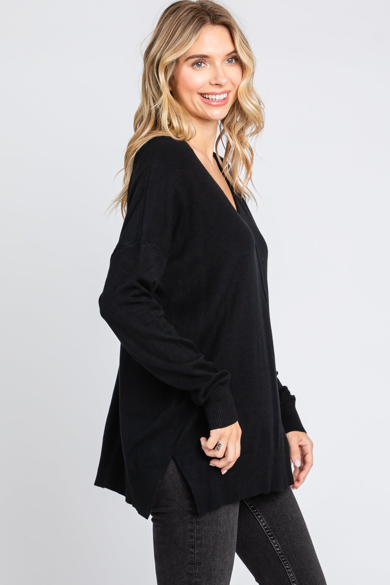 woman wearing a black oversized v-neck sweater paired with dark jeans