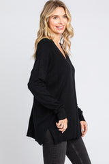 woman wearing a black oversized v-neck sweater paired with dark jeans