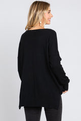 woman wearing a black oversized sweater with a relaxed fit and a rounded hem, shown from the back