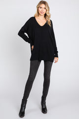 woman wearing a black loose fit v-neck sweater with long sleeves paired with dark skinny jeans and ankle boots