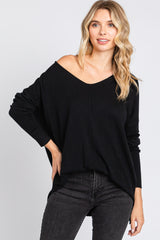 woman wearing a black oversized off-the-shoulder sweater paired with dark skinny jeans
