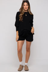 woman wearing a black maternity sweater and matching shorts, styled for comfort and casual wear
