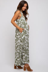 woman wearing a green floral maternity maxi dress with pockets and showing her baby bump