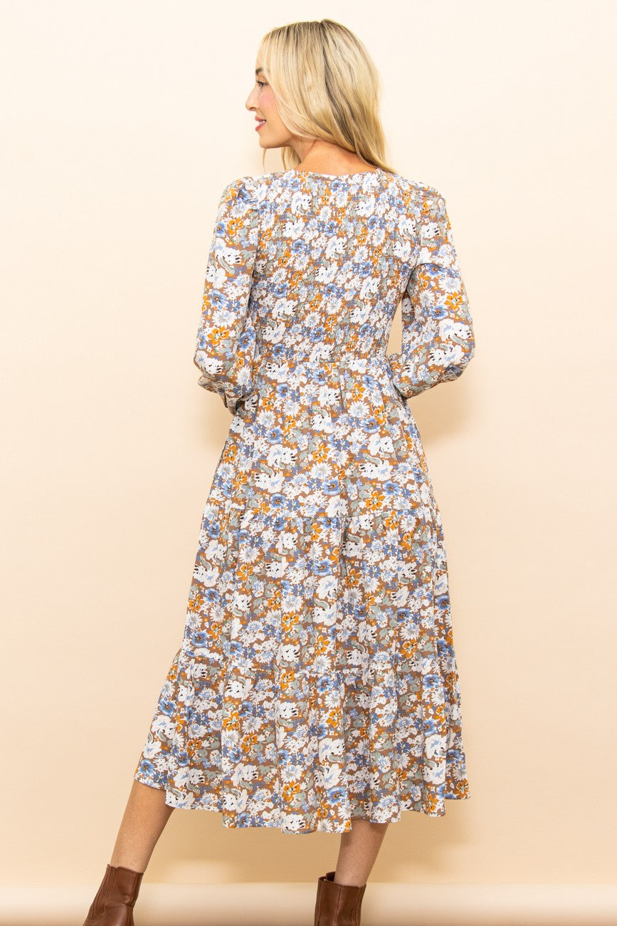 woman wearing a floral long sleeve midi dress with a fitted bodice and flowing skirt, seen from the back