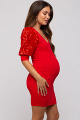woman wearing a red maternity dress with sequin puff sleeves, showcasing her baby bump
