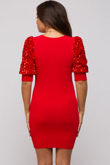woman wearing a red maternity dress with sequin-embellished puff sleeves and a fitted silhouette