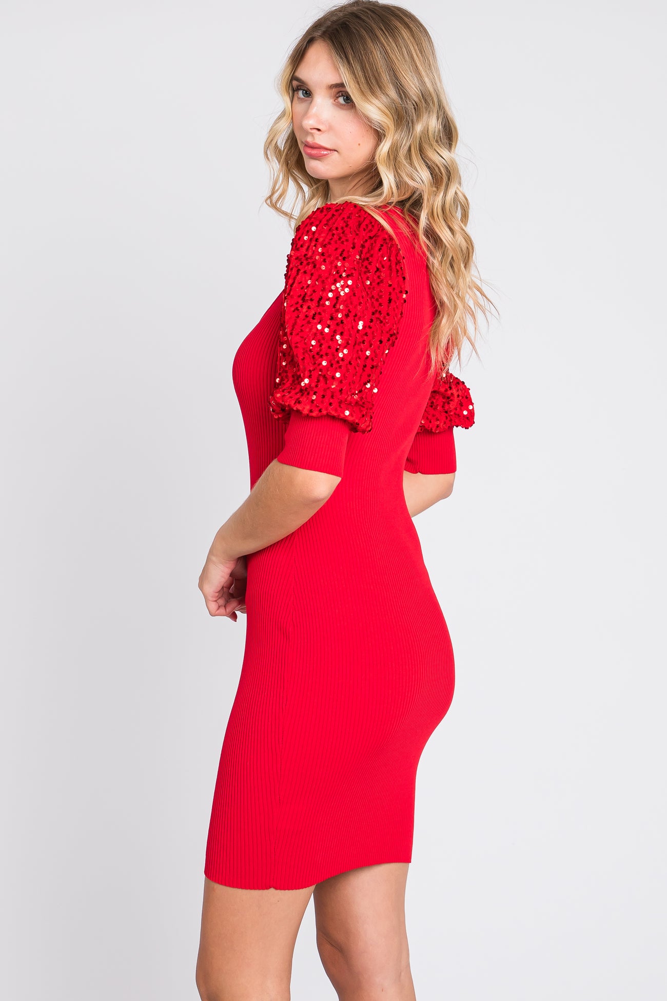woman wearing a red ribbed dress with puffed sequin sleeves, showing the back and side view