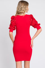 woman wearing a fitted red dress with puffed sequin sleeves, showing the back view