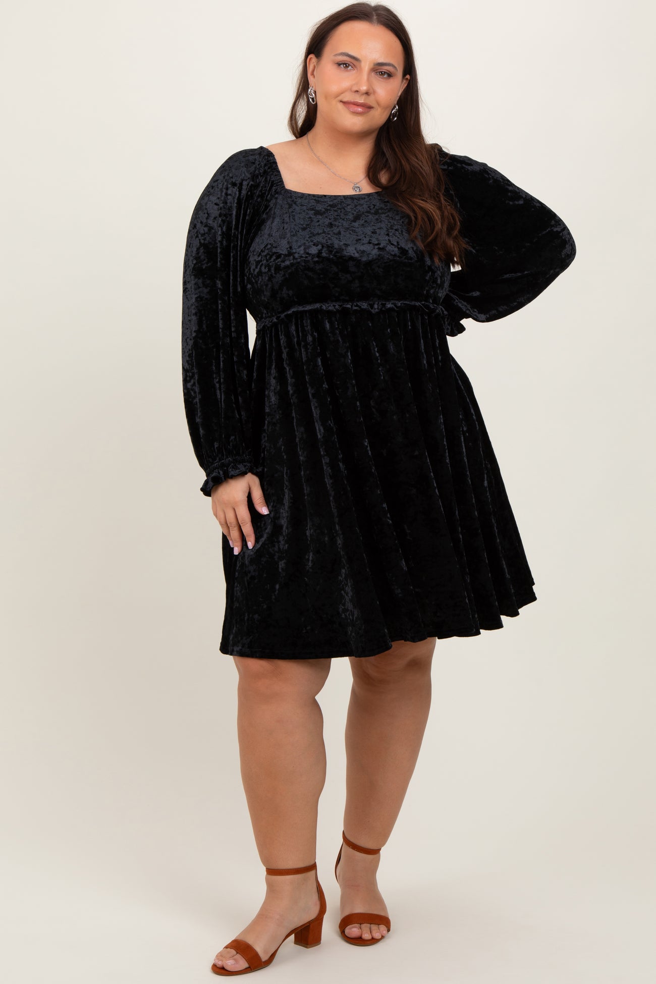 woman wearing a black velvet long sleeve plus size dress with a square neckline and flared skirt