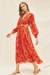 woman wearing orange and red floral maxi dress with waist cutouts and long puff sleeves