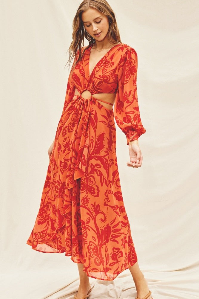 Woman wearing an orange and red floral maxi dress with waist cutouts and long balloon sleeves