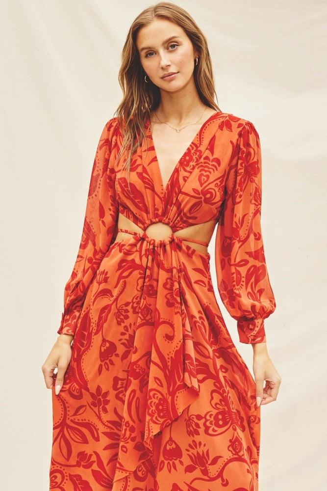 woman wearing a red floral print dress with long sleeves and a knotted cutout detail at the waist