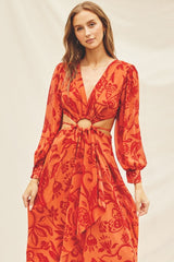 woman wearing a red floral print dress with long sleeves and a knotted cutout detail at the waist