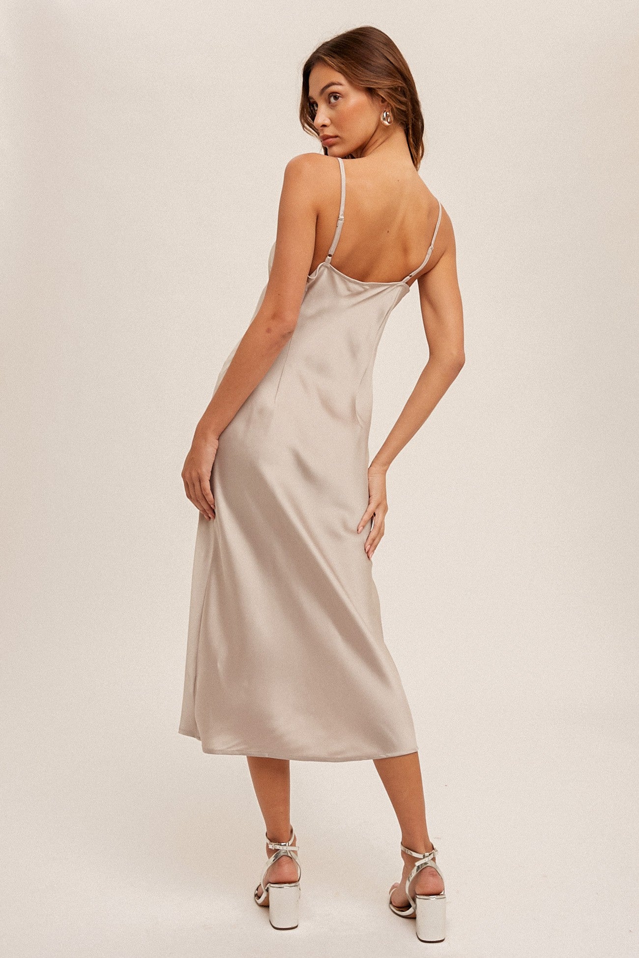 woman wearing a light beige satin midi slip dress with adjustable straps, seen from the back