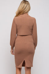 woman wearing a camel-colored maternity dress with long puff sleeves and a back slit detail