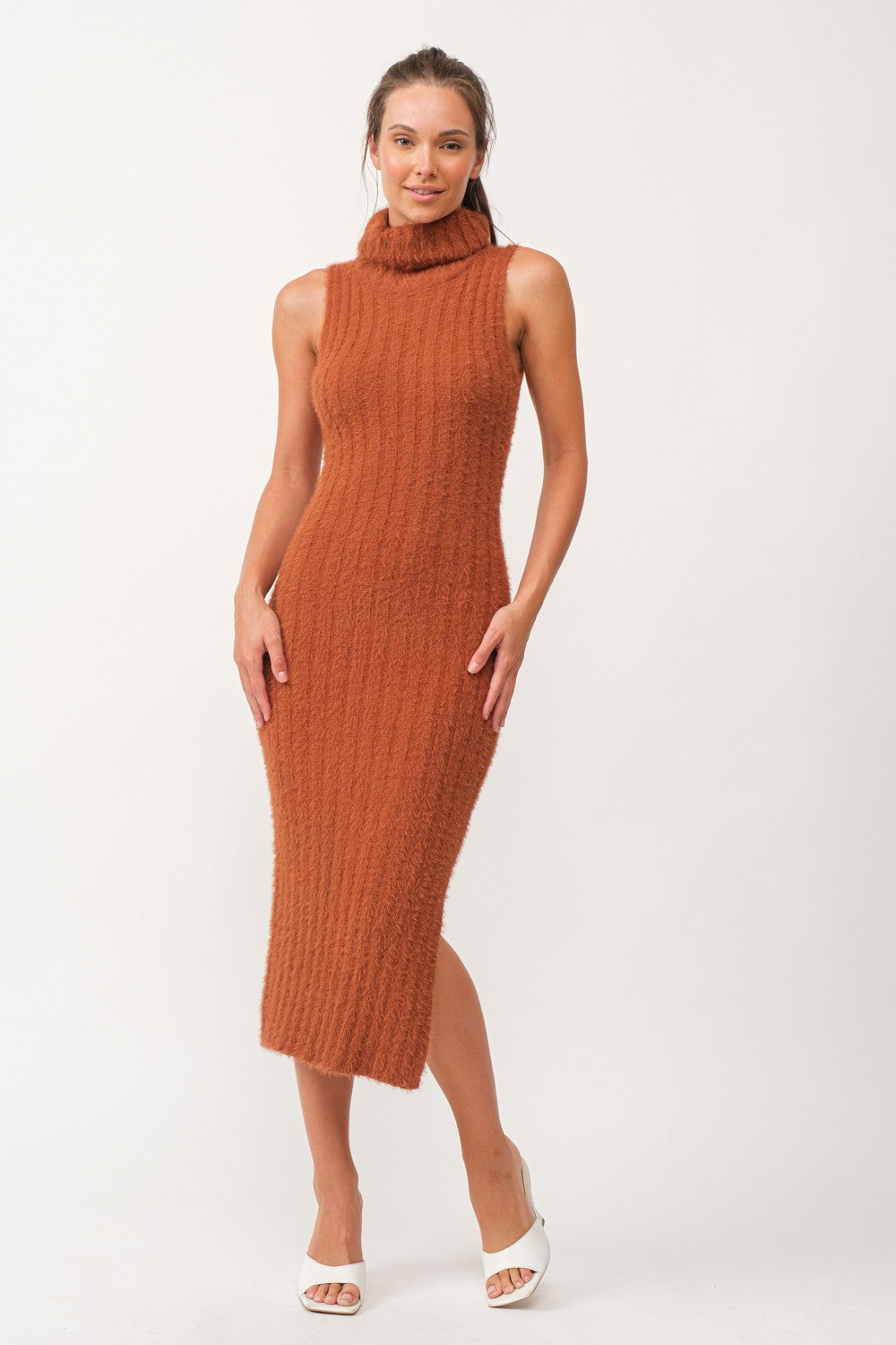 woman wearing a rust-colored sleeveless ribbed midi dress with a high neck and side slit