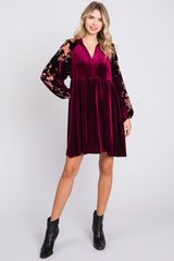 woman wearing a burgundy velvet dress with floral sleeves and a v-neckline, paired with black ankle boots