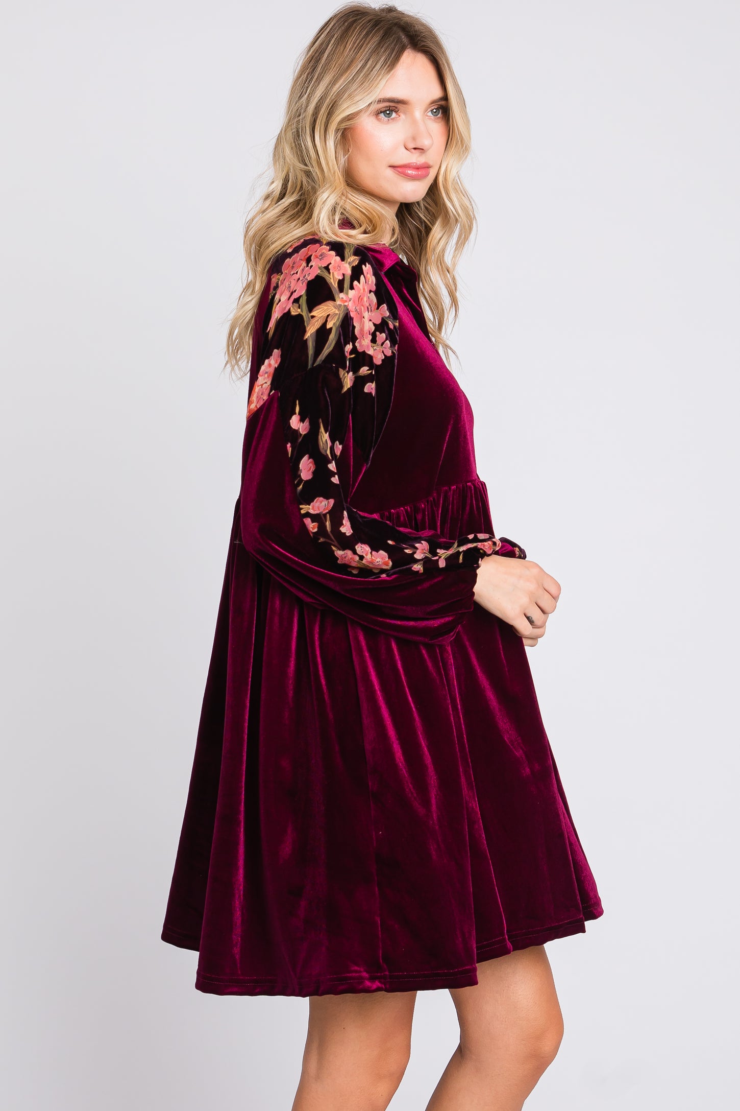 woman wearing a burgundy velvet dress with floral embroidered sleeves and a gathered waist