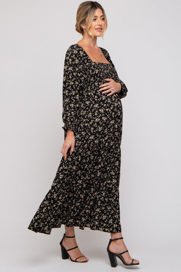 woman wearing a black floral long sleeve maternity dress and holding her baby bump