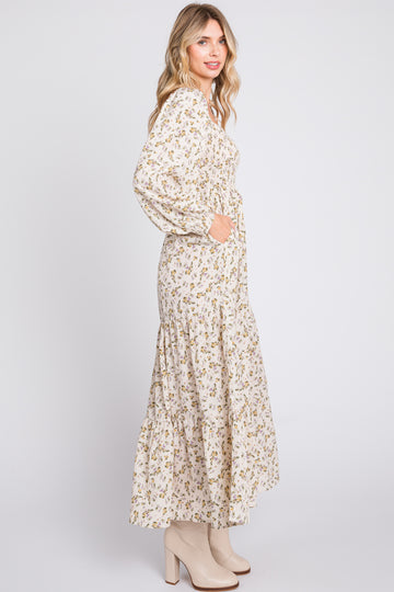 woman wearing a long sleeve floral print maxi dress with a tiered skirt and pockets, paired with beige ankle boots