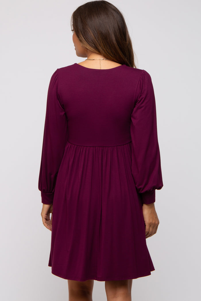 woman wearing a purple long sleeve maternity dress with a fitted bodice and flared skirt, showing the back view
