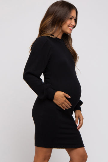woman wearing a black ribbed maternity dress, smiling and holding her baby bump