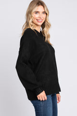woman wearing a black oversized sweater with a relaxed fit and ribbed hem, paired with blue jeans