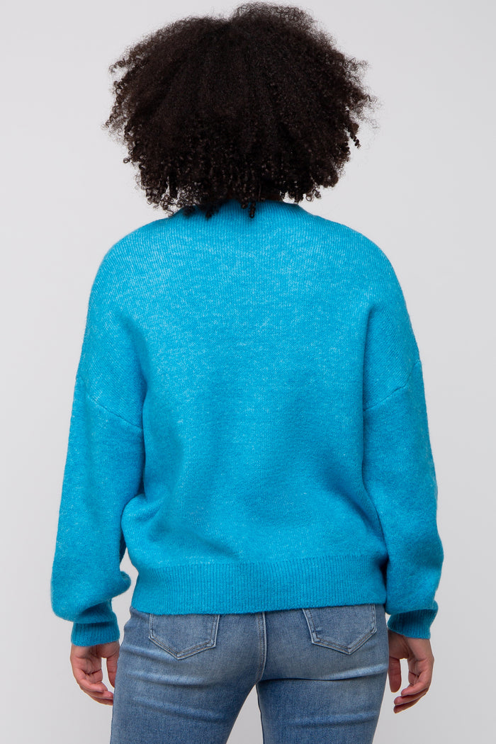 woman wearing a bright blue oversized sweater with a relaxed fit and long sleeves, viewed from the back
