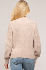 woman wearing a cozy beige maternity sweater with a relaxed fit and balloon sleeves, seen from the back