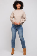 woman wearing a taupe long sleeve sweater and blue straight leg jeans with tan ankle boots