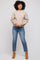 woman wearing a taupe long sleeve sweater and blue straight leg jeans with tan ankle boots